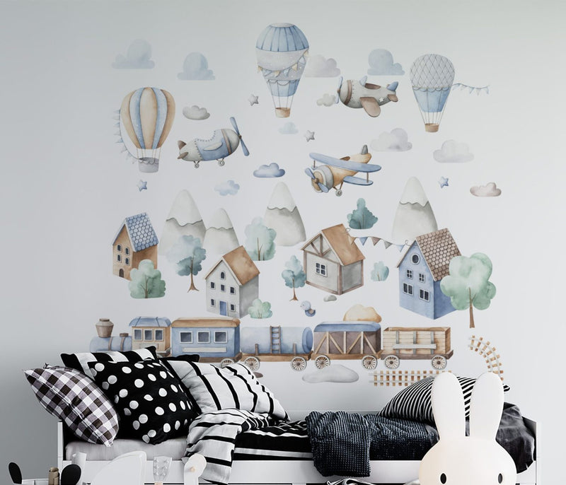 Hot air balloons, airplanes and a train wall stickers arranged across a child's room wall in pastel colours